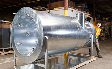 Worker assembling large-scale blow off system with integrated air cannon nozzles